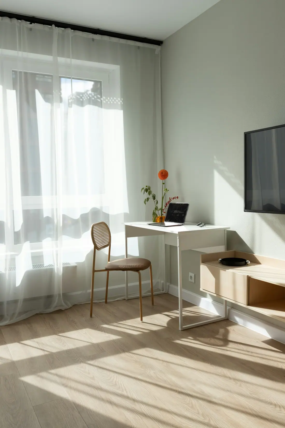 Sunlit room with sheer curtains, a small desk, a chair and a laptop